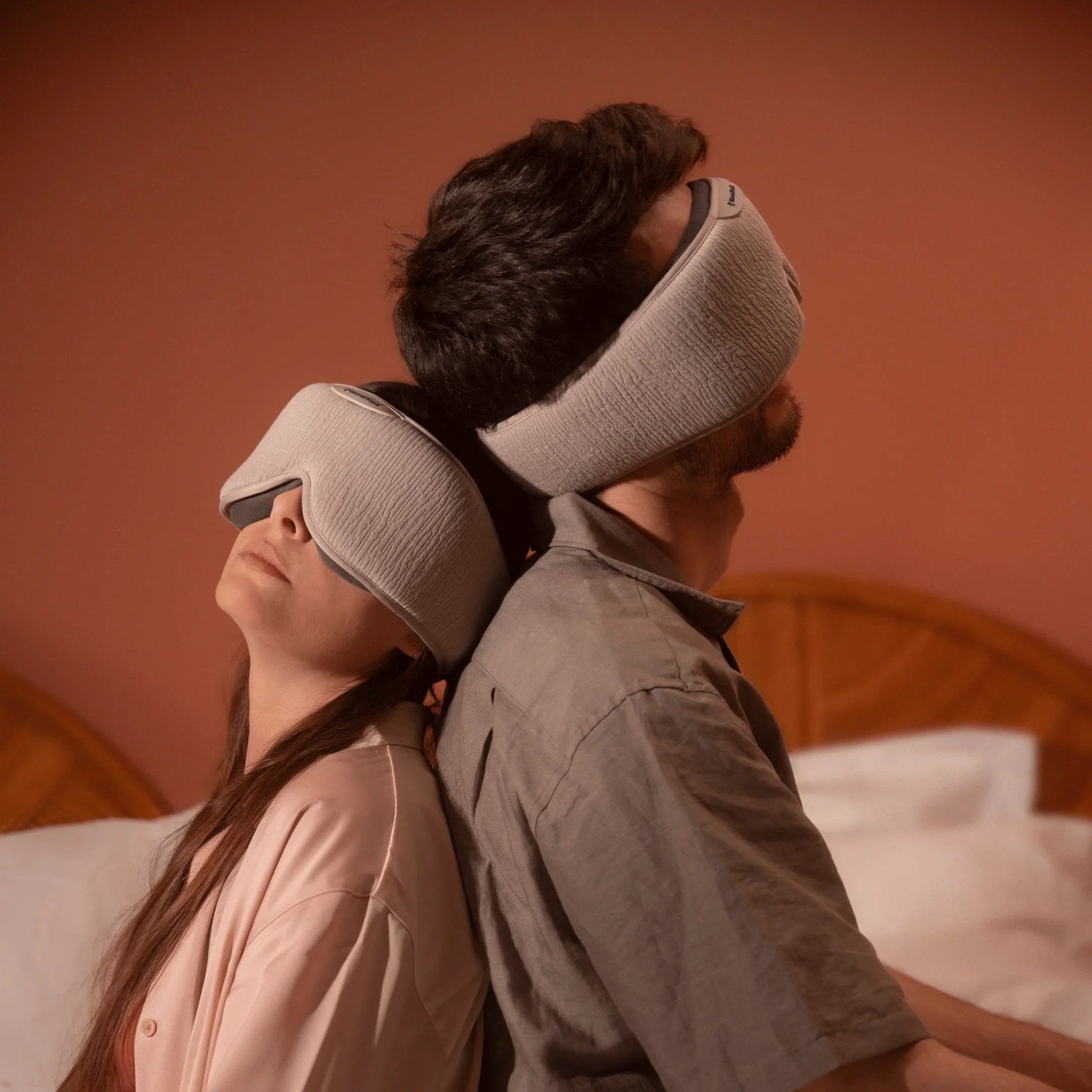 Couple relaxing on bed with gray sleep masks, bedroom background, sleep aid wellness product